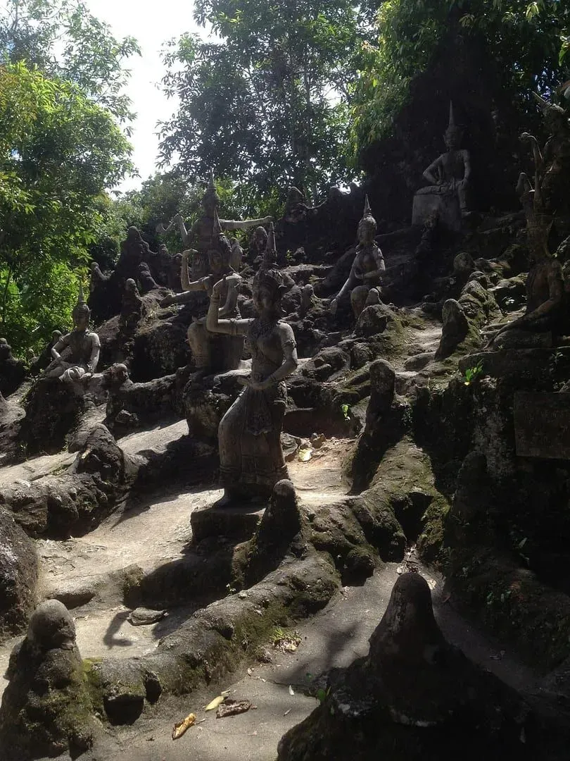 Weathered stone statues on a shaded forest hillside path