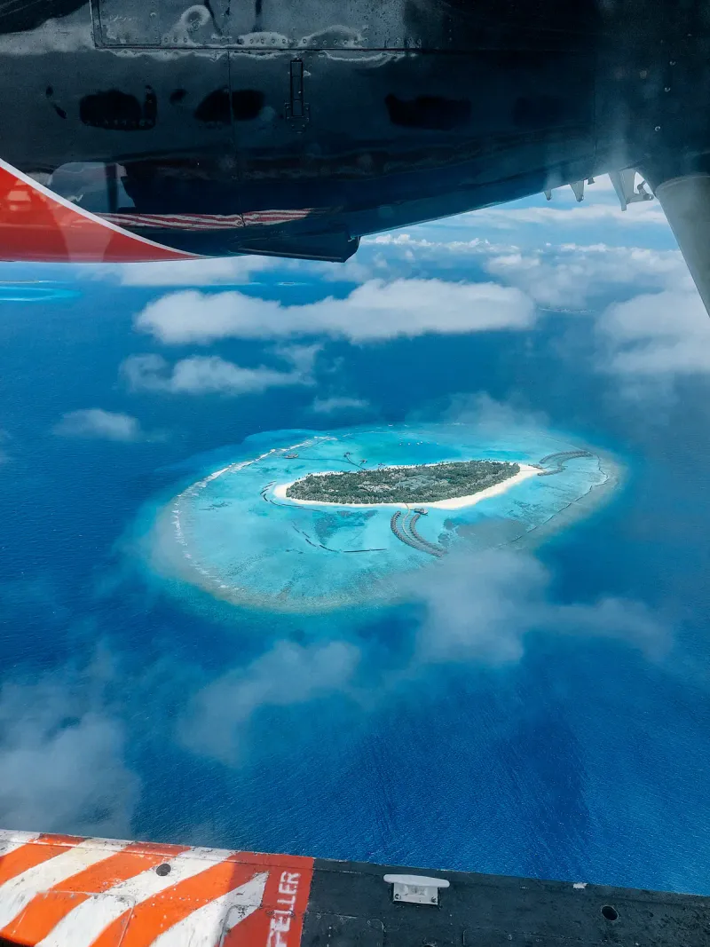 航空機の窓から見た、ターコイズブルーのサンゴ礁に囲まれた小さな熱帯の島