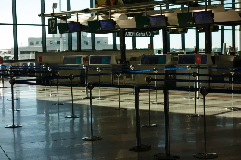 Row of empty airport check-in counters with queue stanchions in front