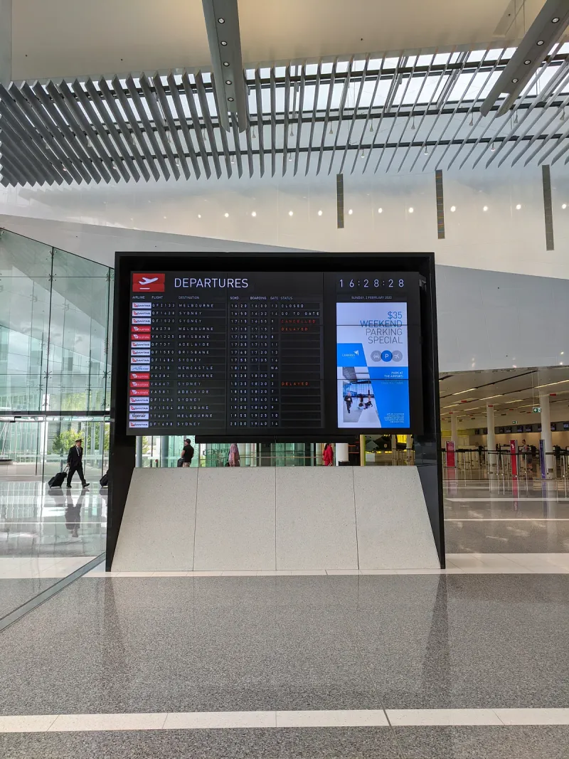 近代的なターミナルにある、時刻、航空会社、ゲートごとに便を表示した空港の出発案内板