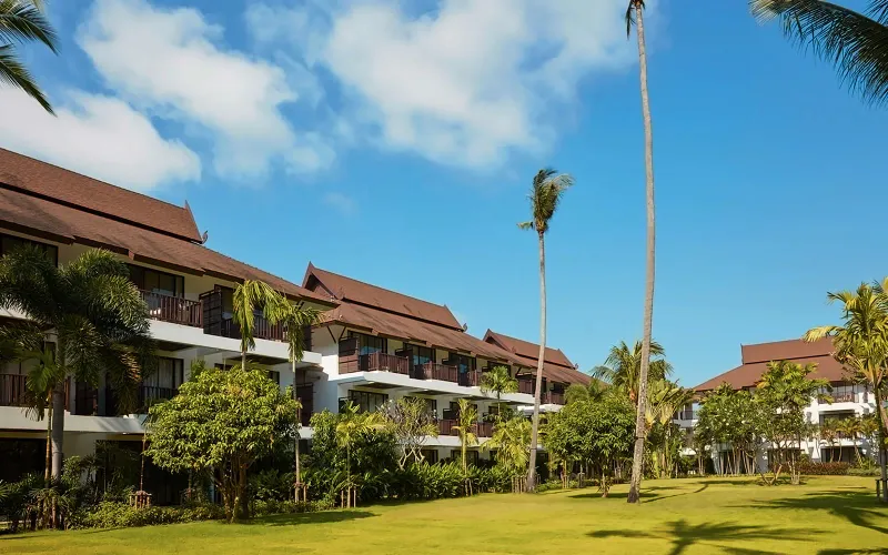 Amari Koh Samui timber guest wings and a wide lawn under palm trees on a sunny day