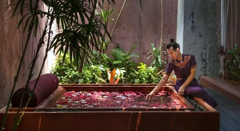 Therapist scattering petals in a flower bath in a spa pavilion at Anantara Bophut Koh Samui