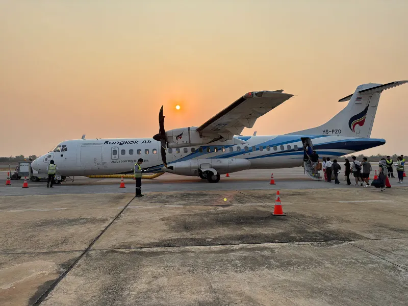 Bangkok Airways ATR 72 turboprop on the apron at sunset with passengers boarding