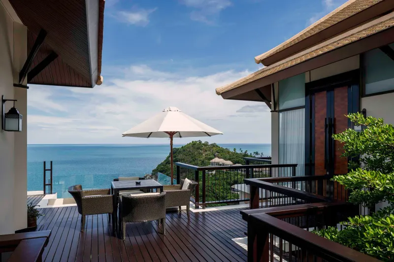 Terrace of a Banyan Tree Samui villa with wicker chairs, a parasol and a long view over the Gulf of Thailand
