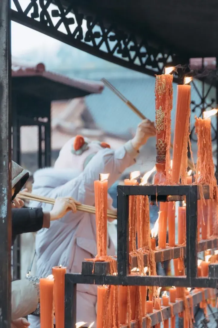 Besucher zünden Kerzen an einem buddhistischen Tempelaltar in Thailand an einem Feiertag an