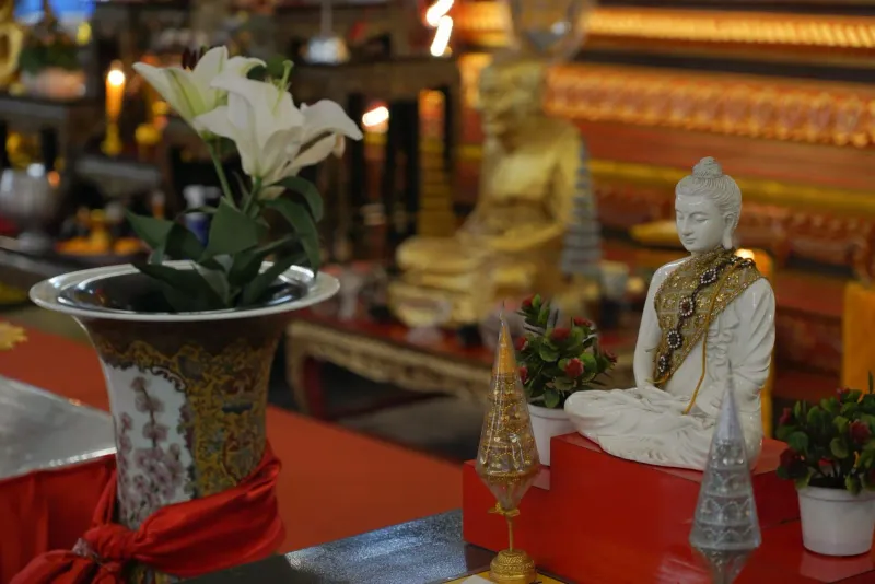 Kunstvoller buddhistischer Altar mit Statue, Blumen und Kerzen für eine Feiertagsopfergabe
