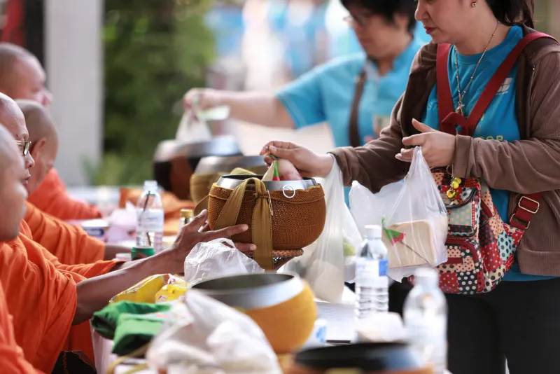 People placing food into monks' bowls
