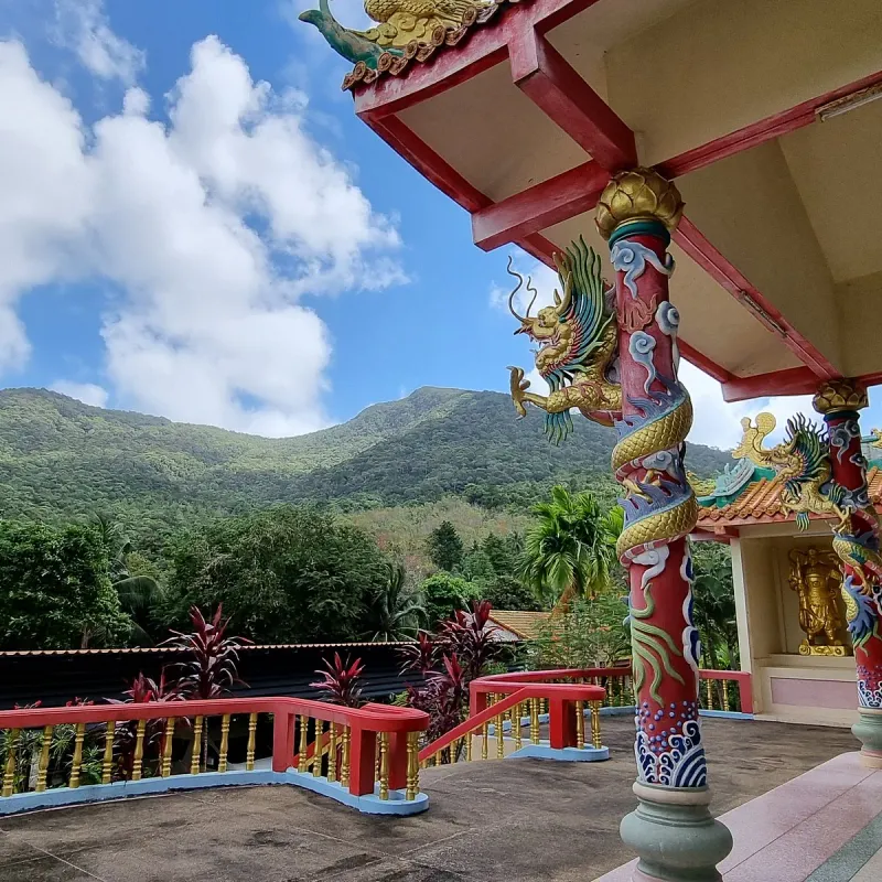 Gold dragon-carved pillar on a terrace overlooking green hills at the Guam Im Shrine