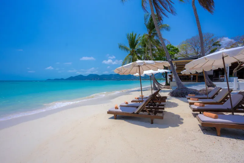 Sonnenliegen und Schirme auf weißem Sand eines Strandresorts in Chaweng auf Koh Samui