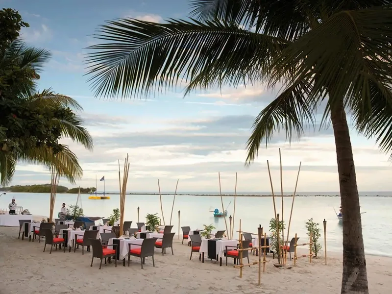 Gedeckte Dinnertische im Sand bei Sonnenuntergang mit Fackeln und Palmen, Chaweng Regent Beach Resort