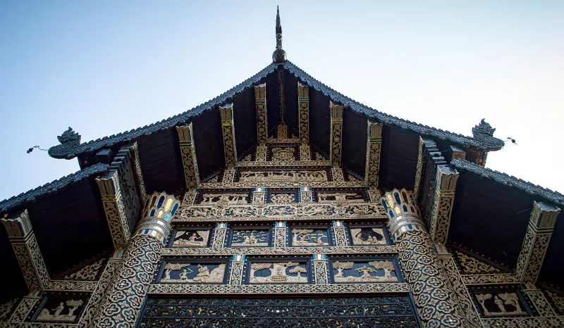 Carved wooden gable of a northern Thai temple under a clear sky in Chiang Mai