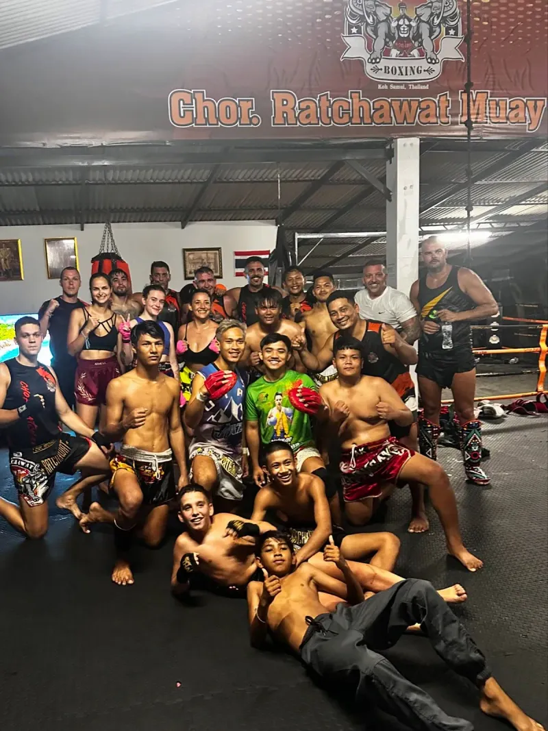 A large group of students and trainers posing after a Muay Thai group class