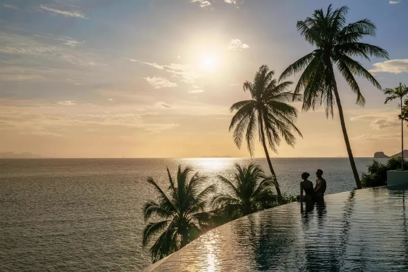 Sunset over the Gulf of Thailand from the Conrad Koh Samui infinity pool with palm silhouettes