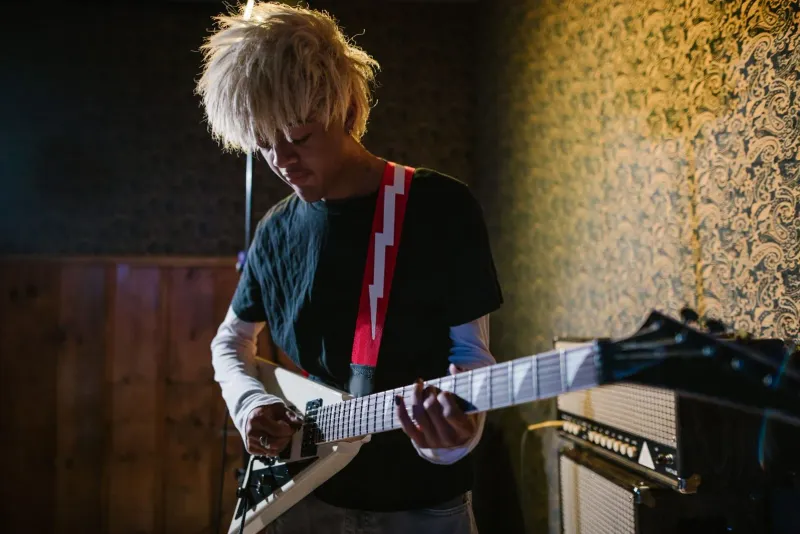 Musiker spielt E-Gitarre in einer gemütlichen Indoor-Proberaum-Umgebung