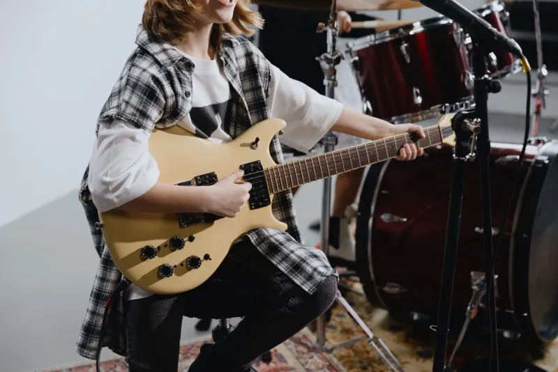Junger Musiker spielt E-Gitarre, die Art von Spieler im Schulalter, der in einem Gemeinschafts-Musikraum probt