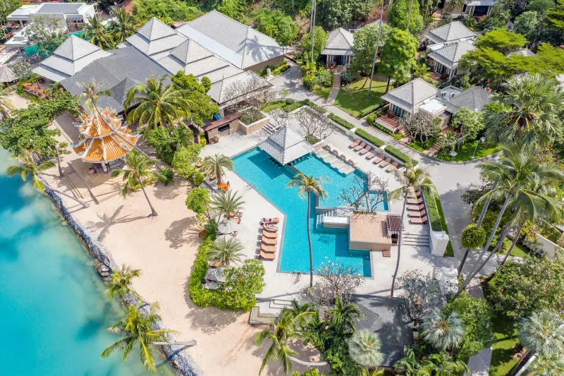 Aerial view of the Fair House Villas & Spa pool, sandy beachfront and orange pagoda roof surrounded by palms