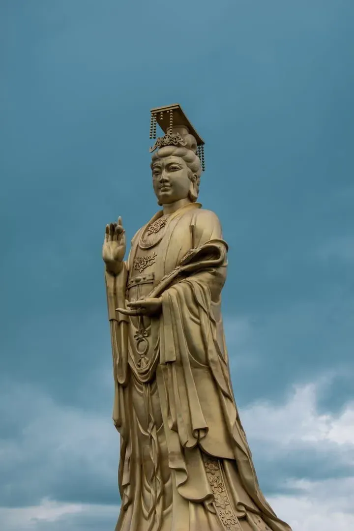 A majestic Guanyin statue standing tall against a cloudy sky on Mount Putuo, China