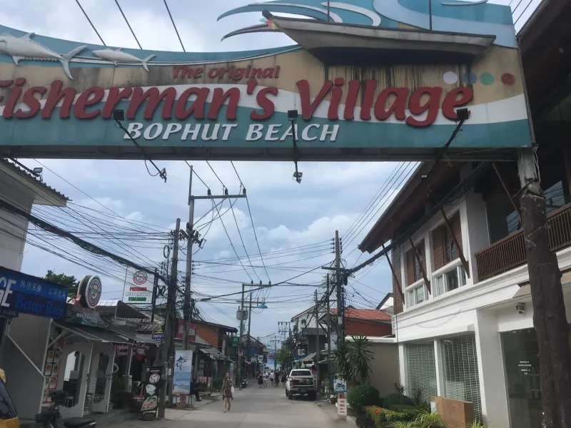 The original Fisherman's Village Bophut Beach archway sign at the entrance to the strip where Samui Boat Charter's office sits