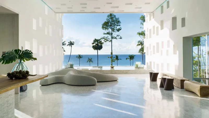 Open-air lobby of Hyatt Regency Koh Samui with a sculpted sofa and the sea framed between white perforated walls