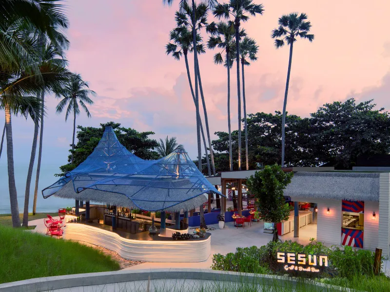 Sesun Grill and Beach Bar at dusk with a blue net canopy, thatched roof and lit bar counter at Hyatt Regency Koh Samui