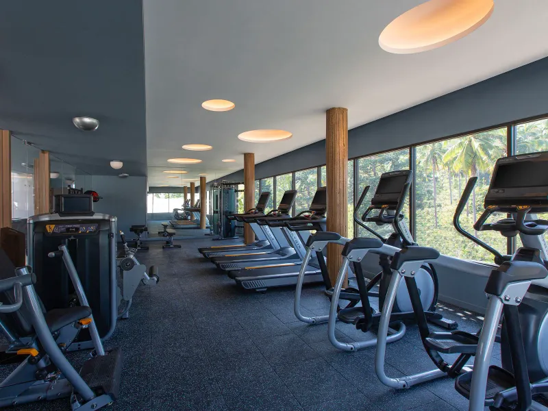 Fitness centre with treadmills, cross-trainers and tall windows onto palm trees at Hyatt Regency Koh Samui