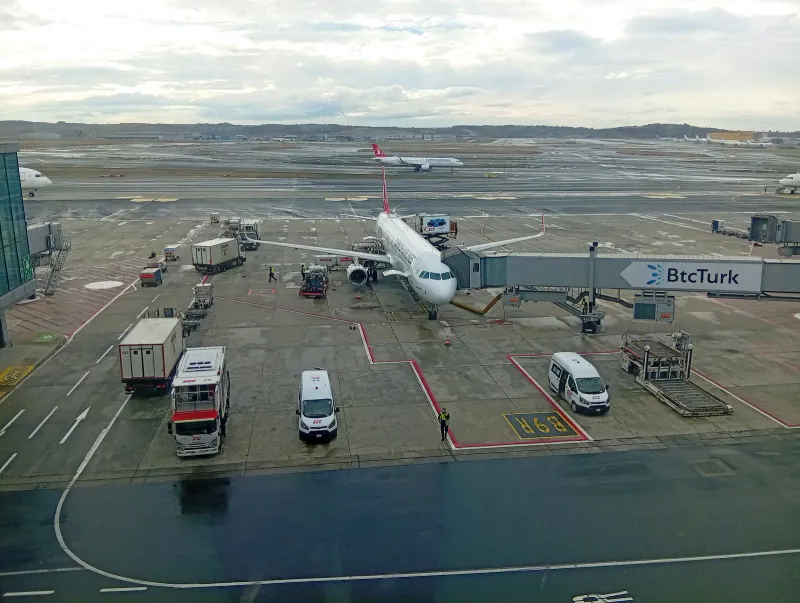 Turkish Airlines plane on the tarmac beside a boarding gate at Istanbul Airport