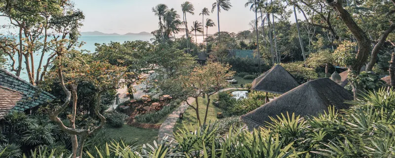 Aerial view of the Kamalaya resort's thatched pavilion roofs set among jungle and sea