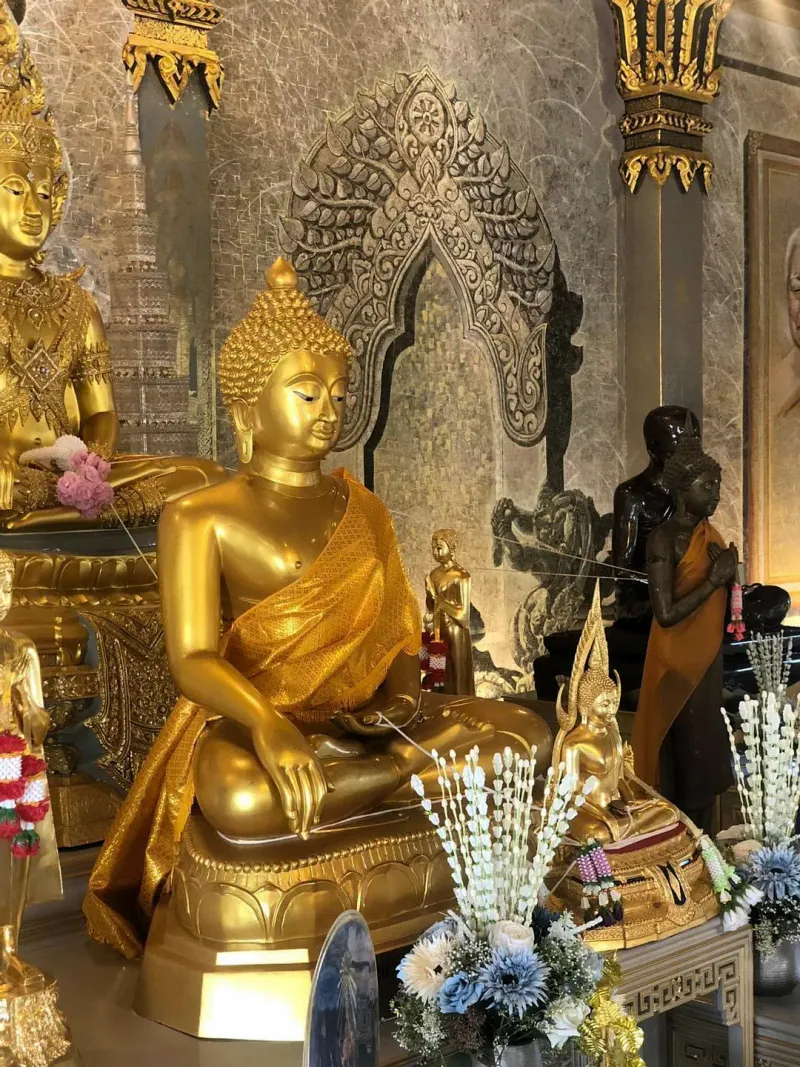 Golden Buddha statue seated among smaller gilded figures inside the temple hall