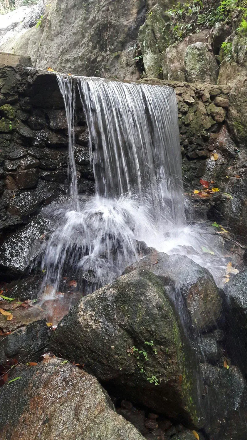 A smaller cascade at Khao Yai spilling over a stacked-stone ledge into a catch pool