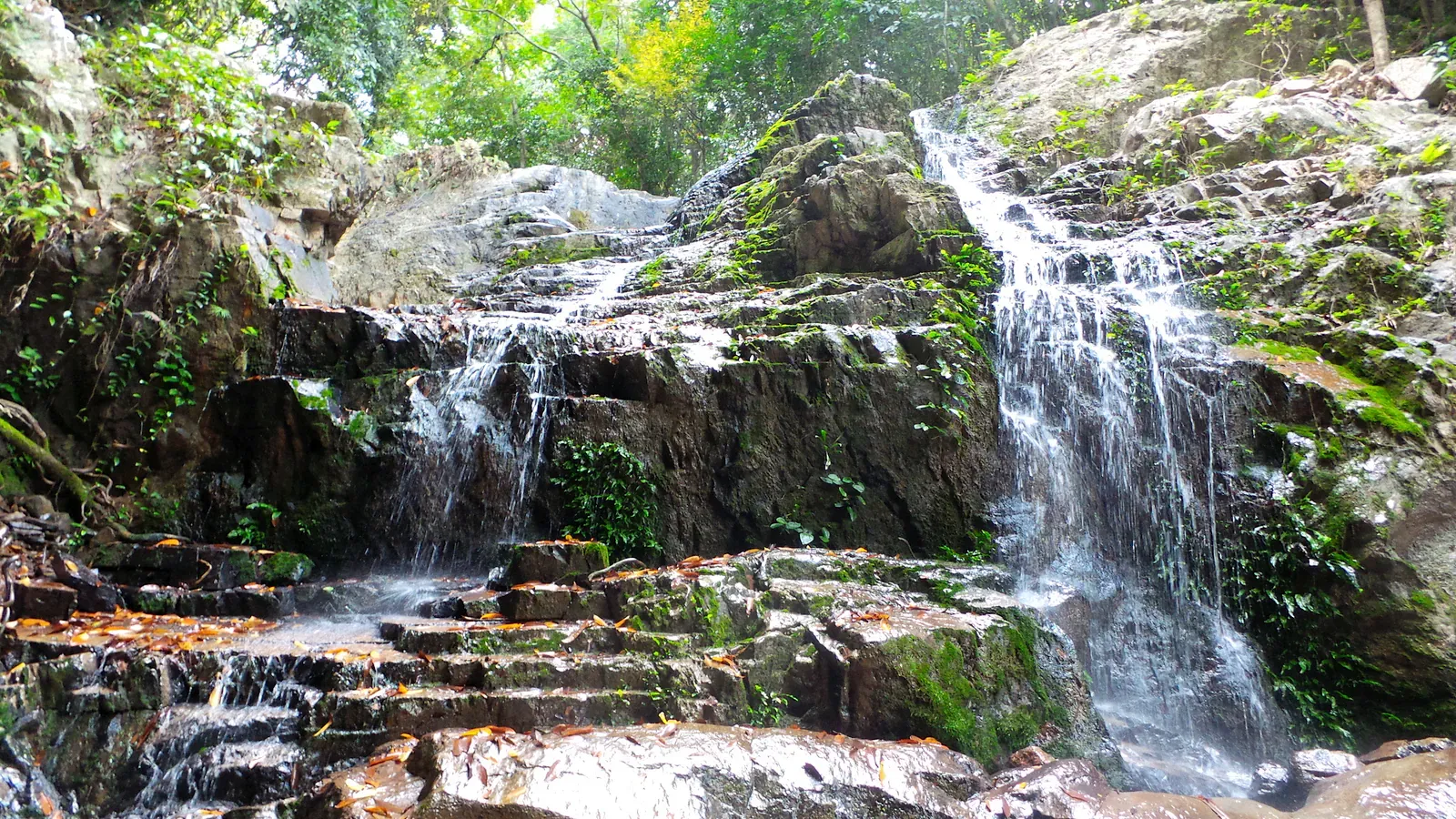 Water flowing over rocks at the lower tiers of Khun Si Waterfall