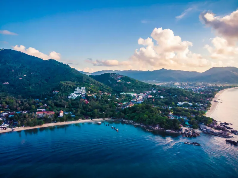 Aerial view of a hilly Koh Samui coast with bay, rocks and houses near Lamai under evening clouds