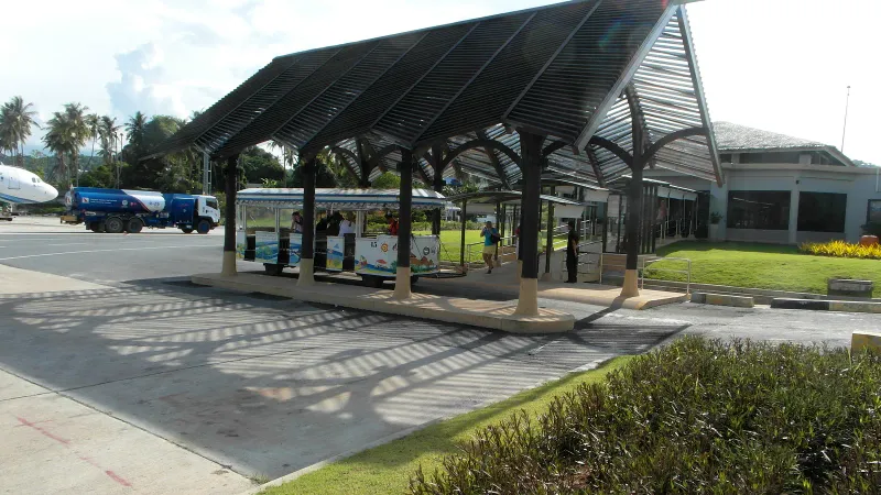 Covered shuttle waiting area beside the open-air terminal at Koh Samui Airport