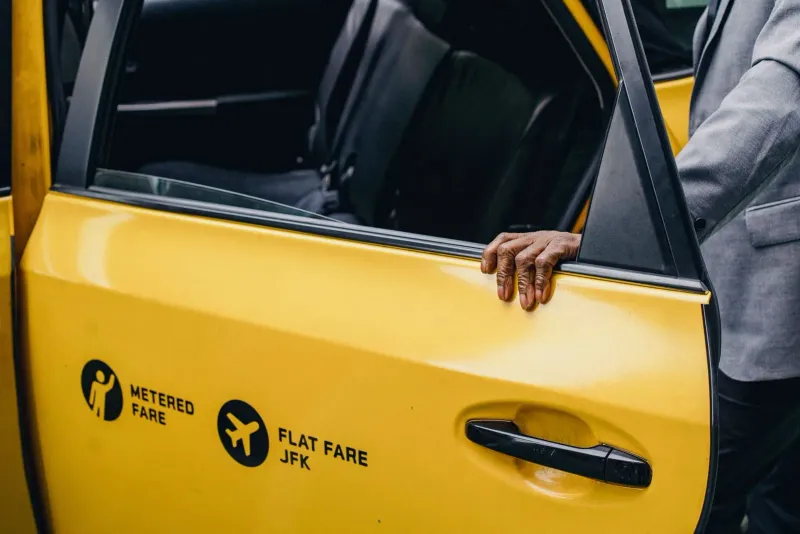 Viaggiatore che apre la portiera di un taxi con i bagagli dopo l'arrivo all'aeroporto di Koh Samui per il transfer a Chaweng