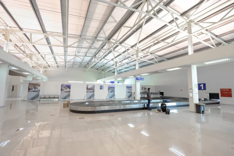 Traveler waiting in a quiet airport baggage claim area, similar to the Koh Samui Airport arrivals hall