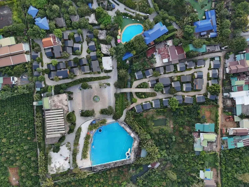 Aerial view of a hillside resort with pools and villas above the Gulf of Thailand