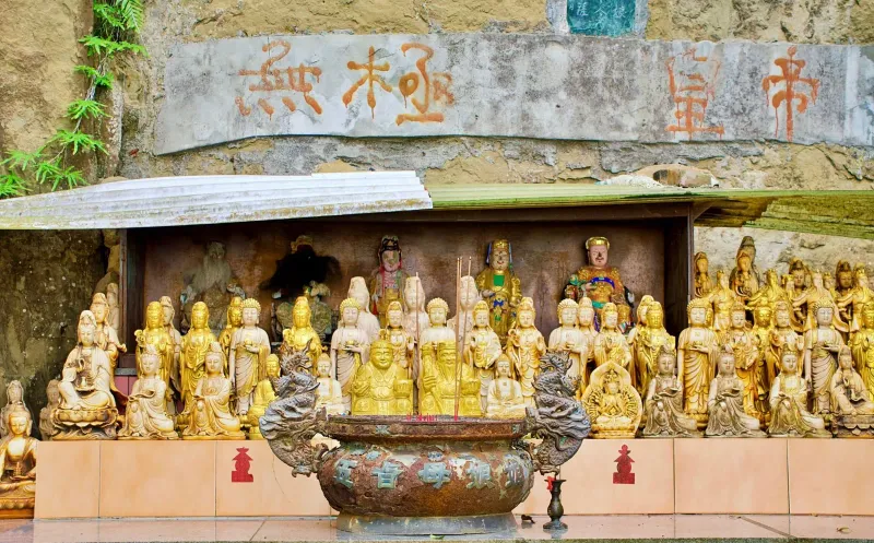 Golden Chinese deity statues and calligraphy inside a temple altar, the interior style found at Samui's Hainanese shrines