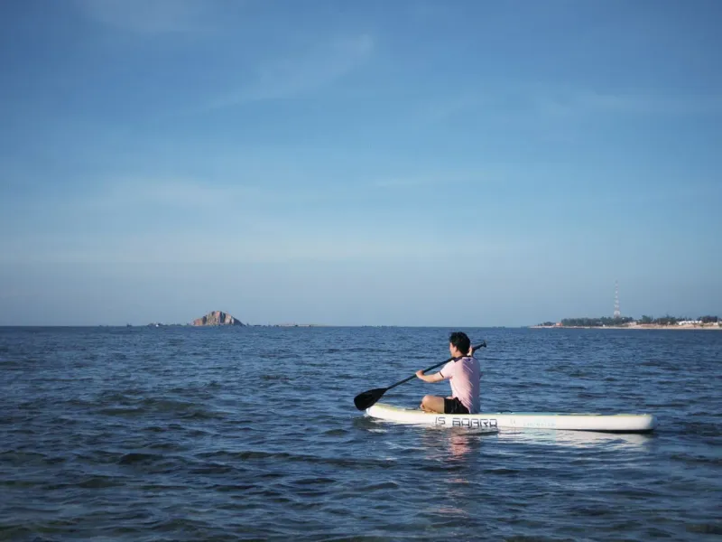 A paddler alone on flat, glassy water, the calm morning conditions that suit foiling around Koh Samui