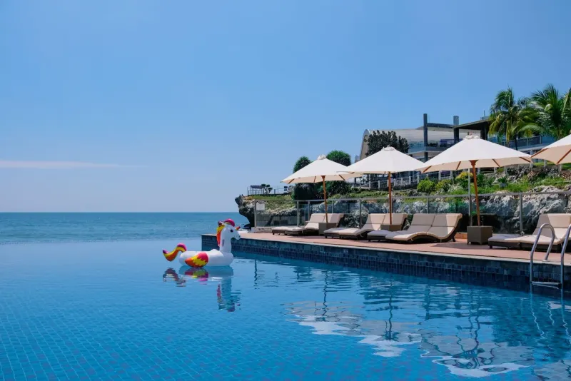 Beachside infinity pool with sunbeds and umbrellas near a tropical resort in Koh Samui