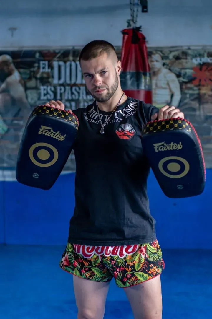 Man holding focus pads in a Muay Thai gym, ready to run pad drills for a Yodyut Muaythai group class