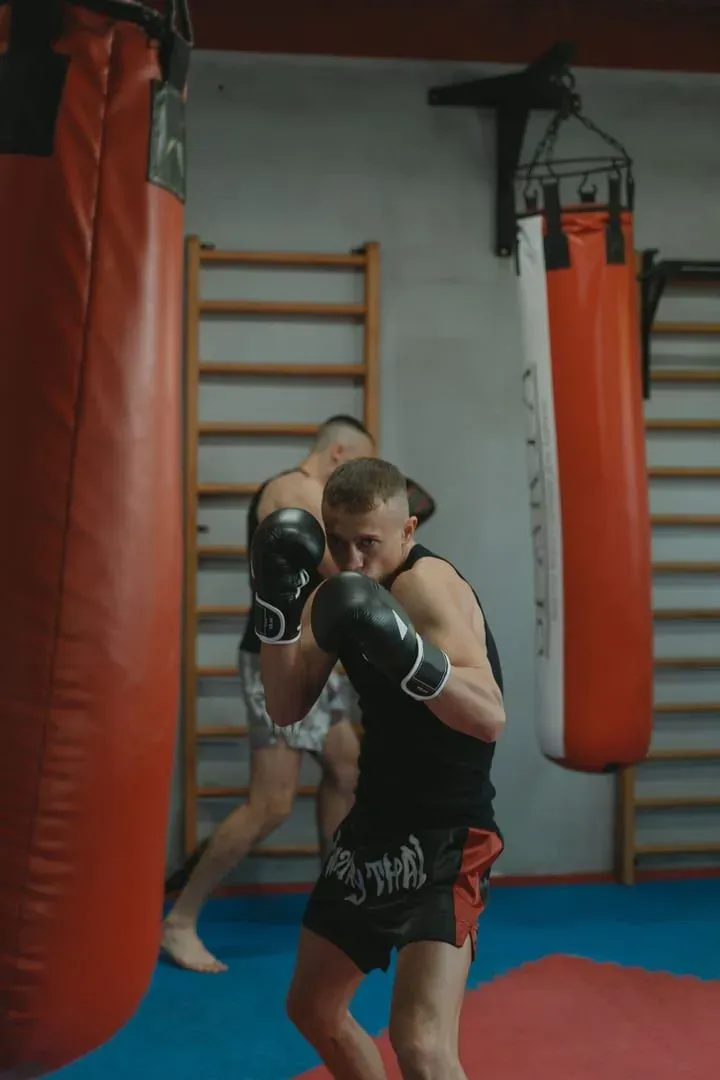 Two men practicing Muay Thai bag work in a gym, the conditioning drills that close out sessions at Yodyut Muaythai