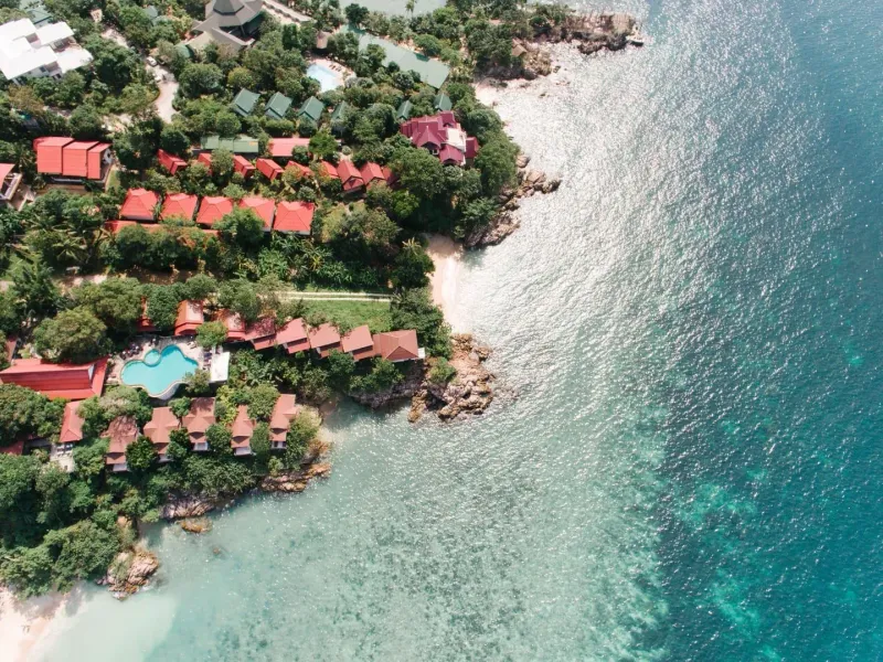 Aerial view of a tropical Koh Samui coastline with villas, lush greenery and clear turquoise water