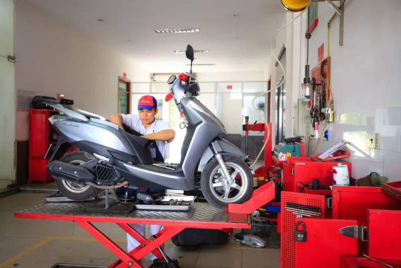 Mechanic inspecting a rented scooter for pre-existing damage in Thailand
