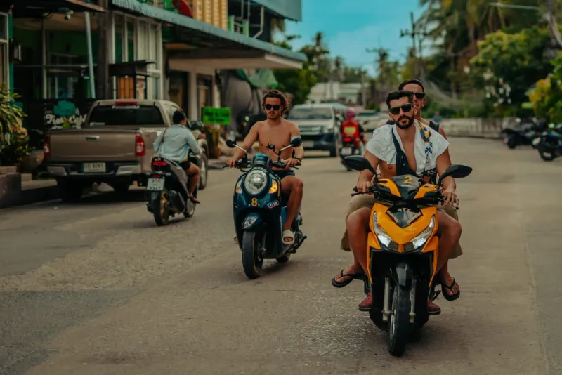 Group riding scooters along a tropical street typical of independent travel around Koh Samui