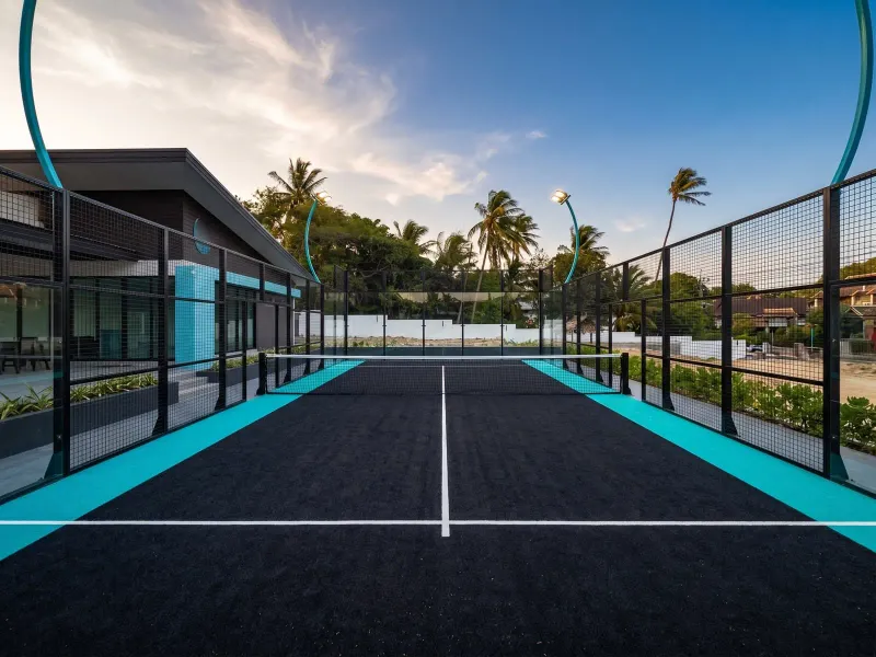 A padel court with glass walls beside palm trees on Koh Samui