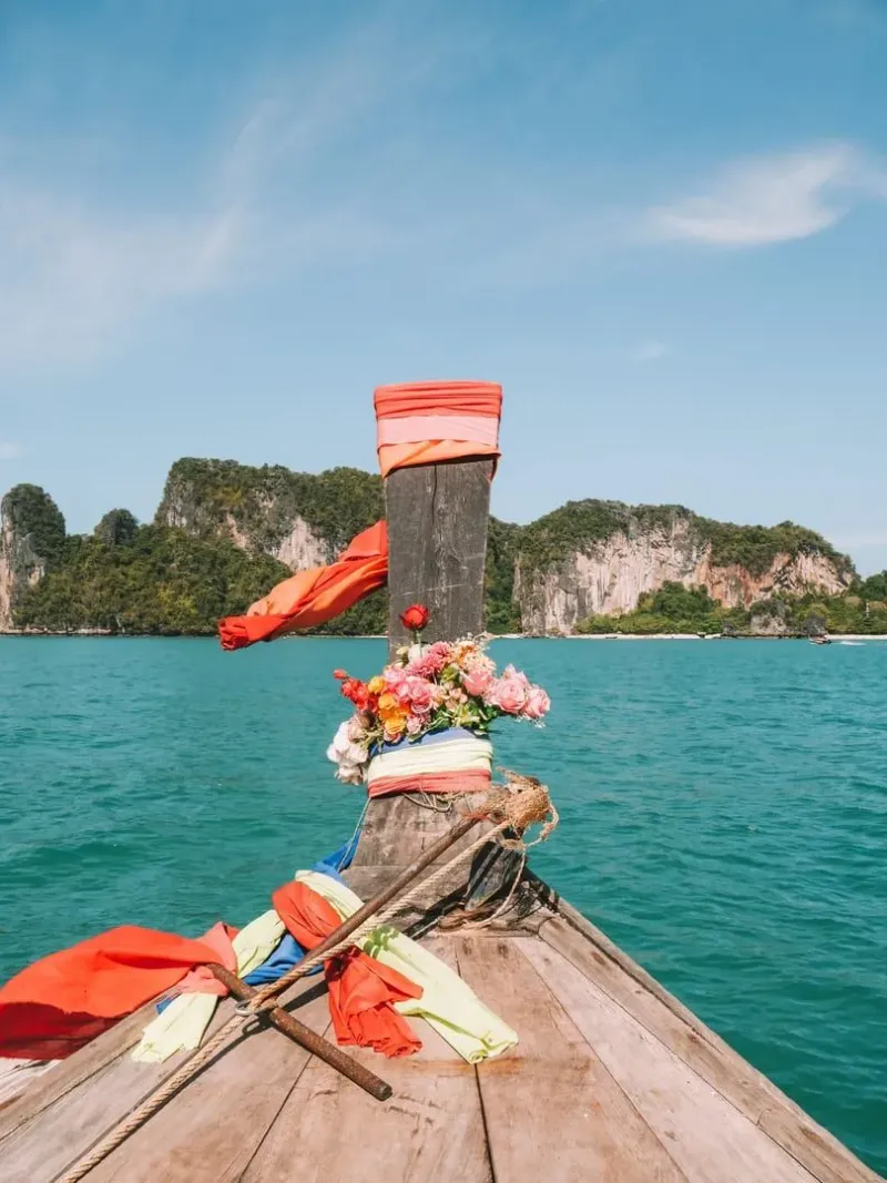 Decorated longtail boat on turquoise water with Krabi's limestone cliffs behind it