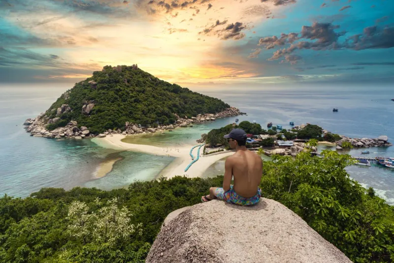 Visitor watching a sunset panorama from a Gulf of Thailand island viewpoint near Koh Samui