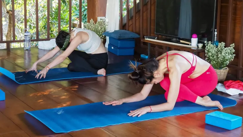 Women stretching on yoga mats together indoors during a group class