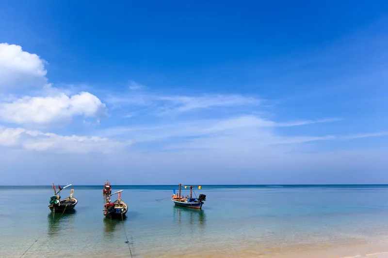 Three fishing boats anchored in calm water off Laem Yai