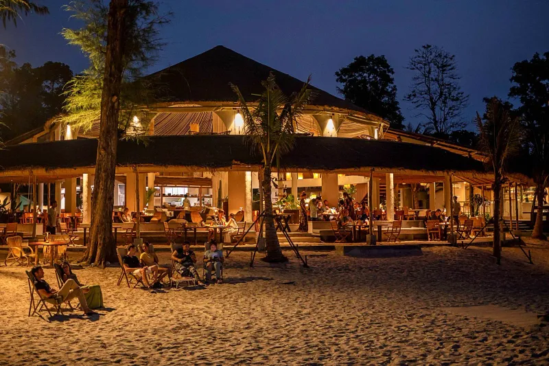 A lantern-lit beachside restaurant on the sand at night