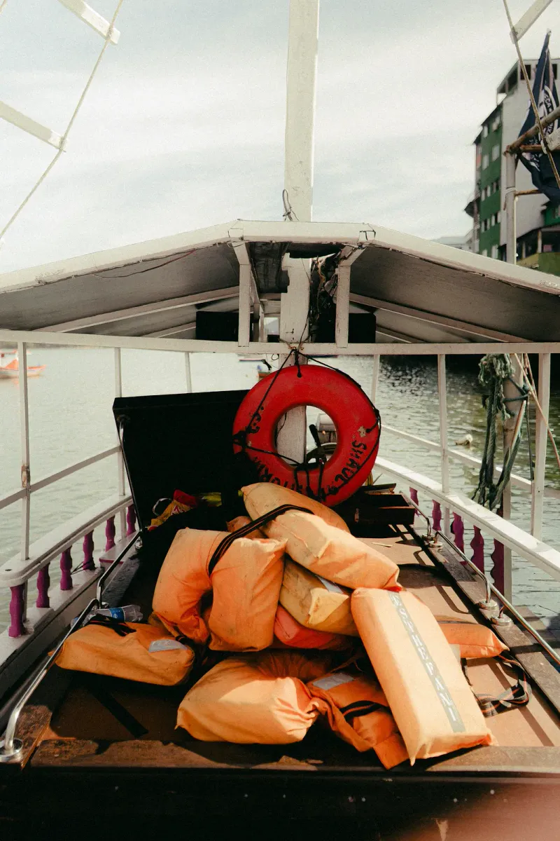 Stack of life jackets and a lifebuoy stored on a docked boat ready for passengers